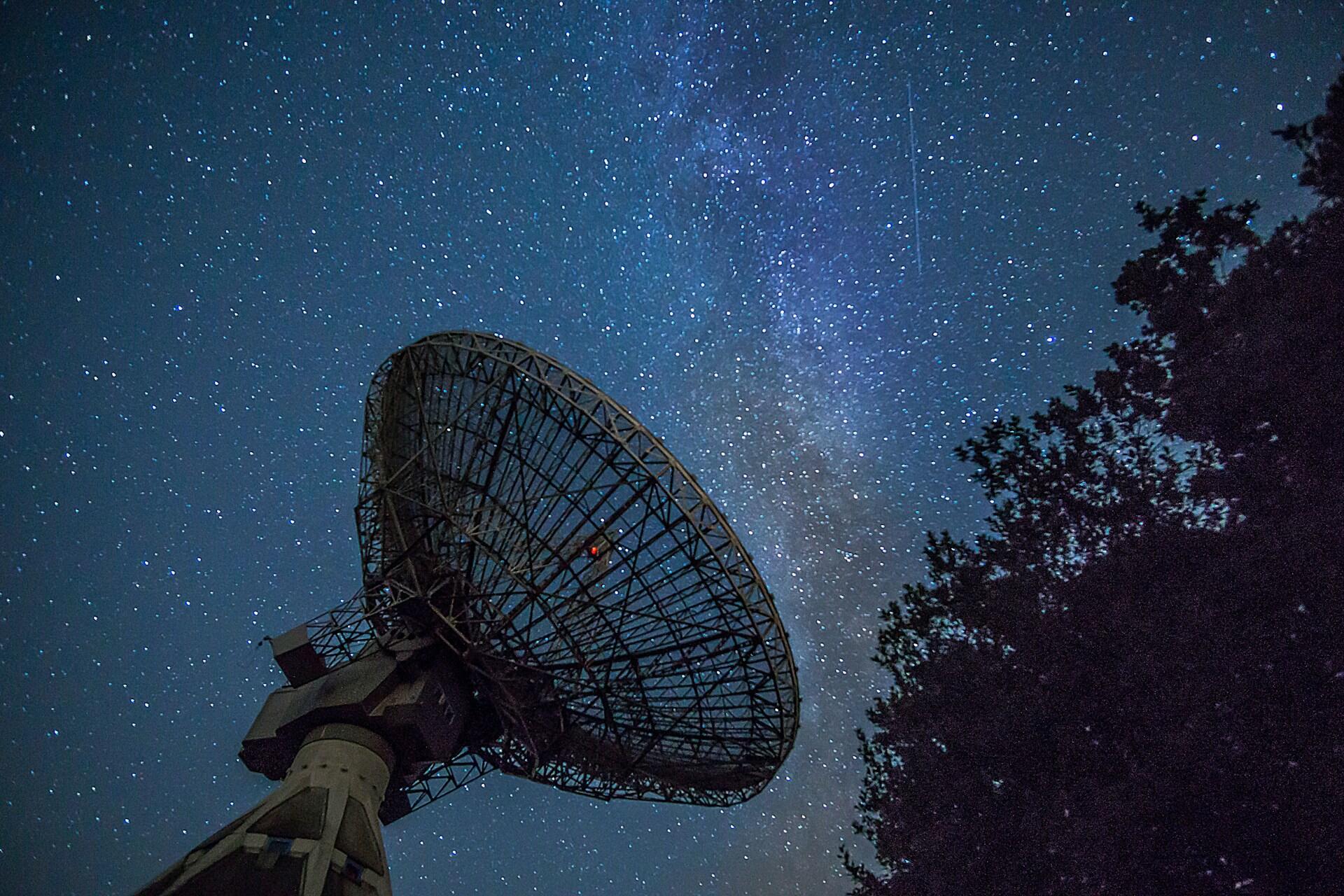 Großes Teleskop vor dunklem Sternenhimmel.