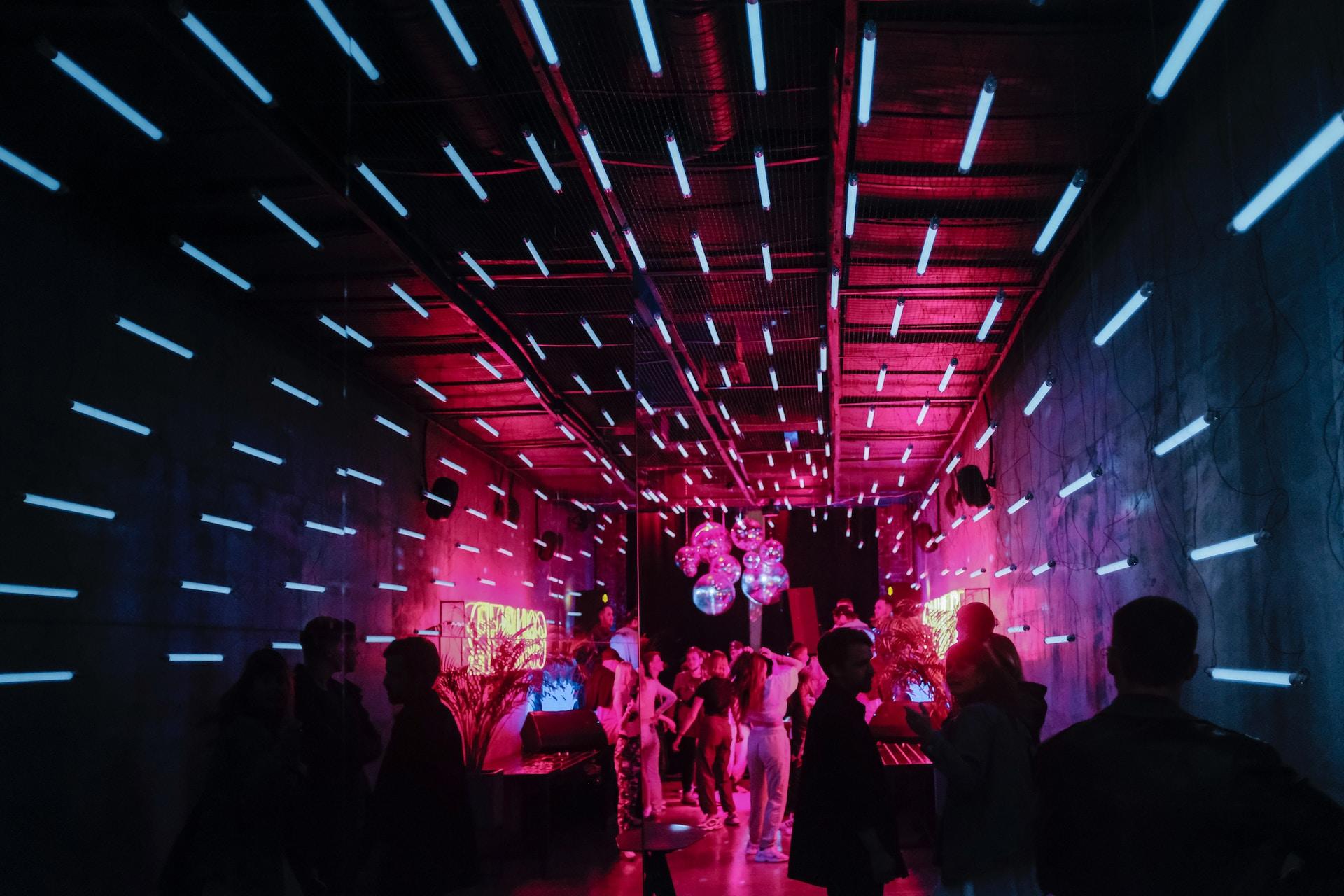Ein Privatraum mit hellen Streifen als Projektionen an den Wänden und pink Licht und im Hintergrund ist eine kleine Tanz-Party.