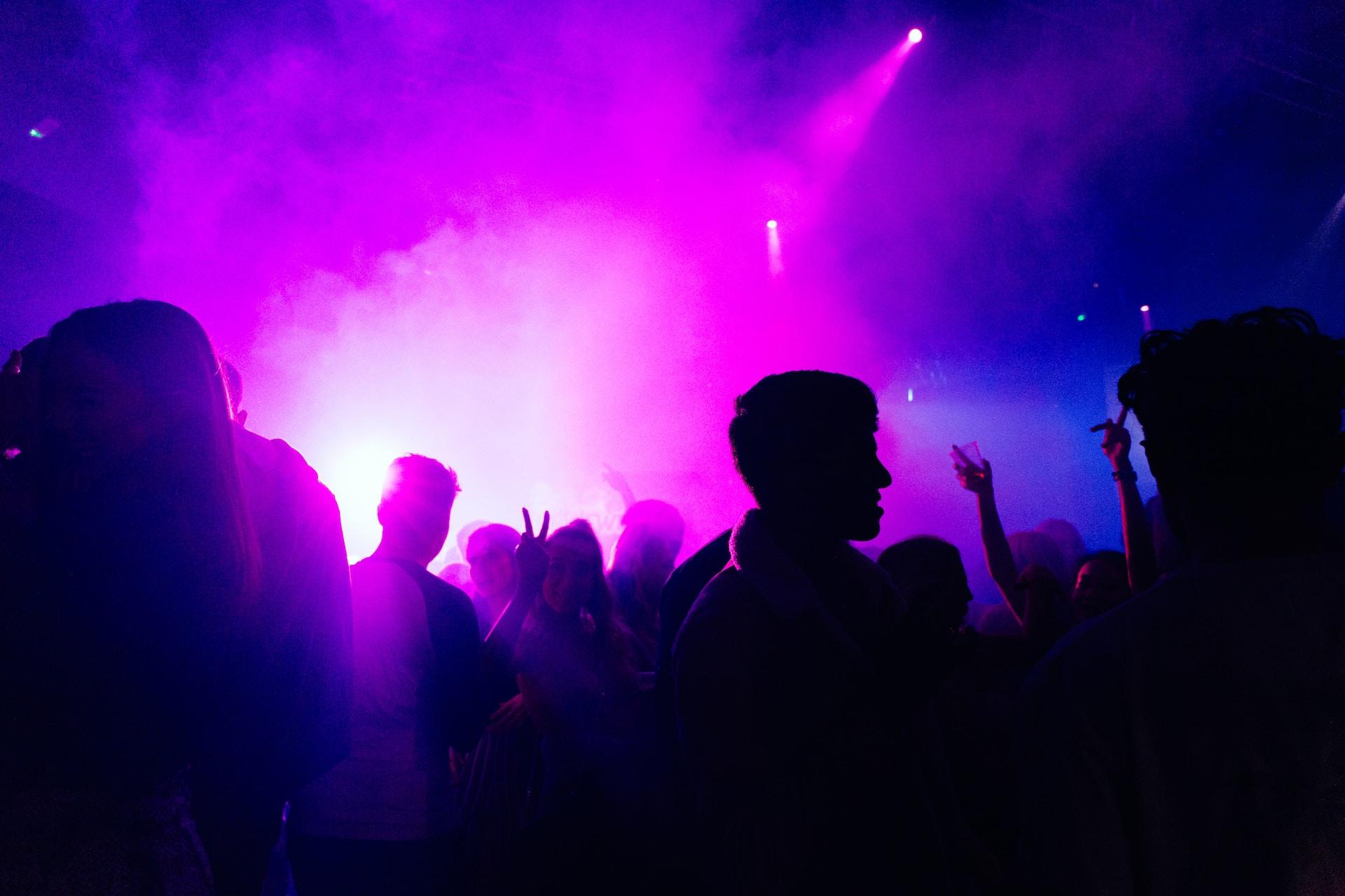Leute die tanzen in einer Disco bei pink Licht.
