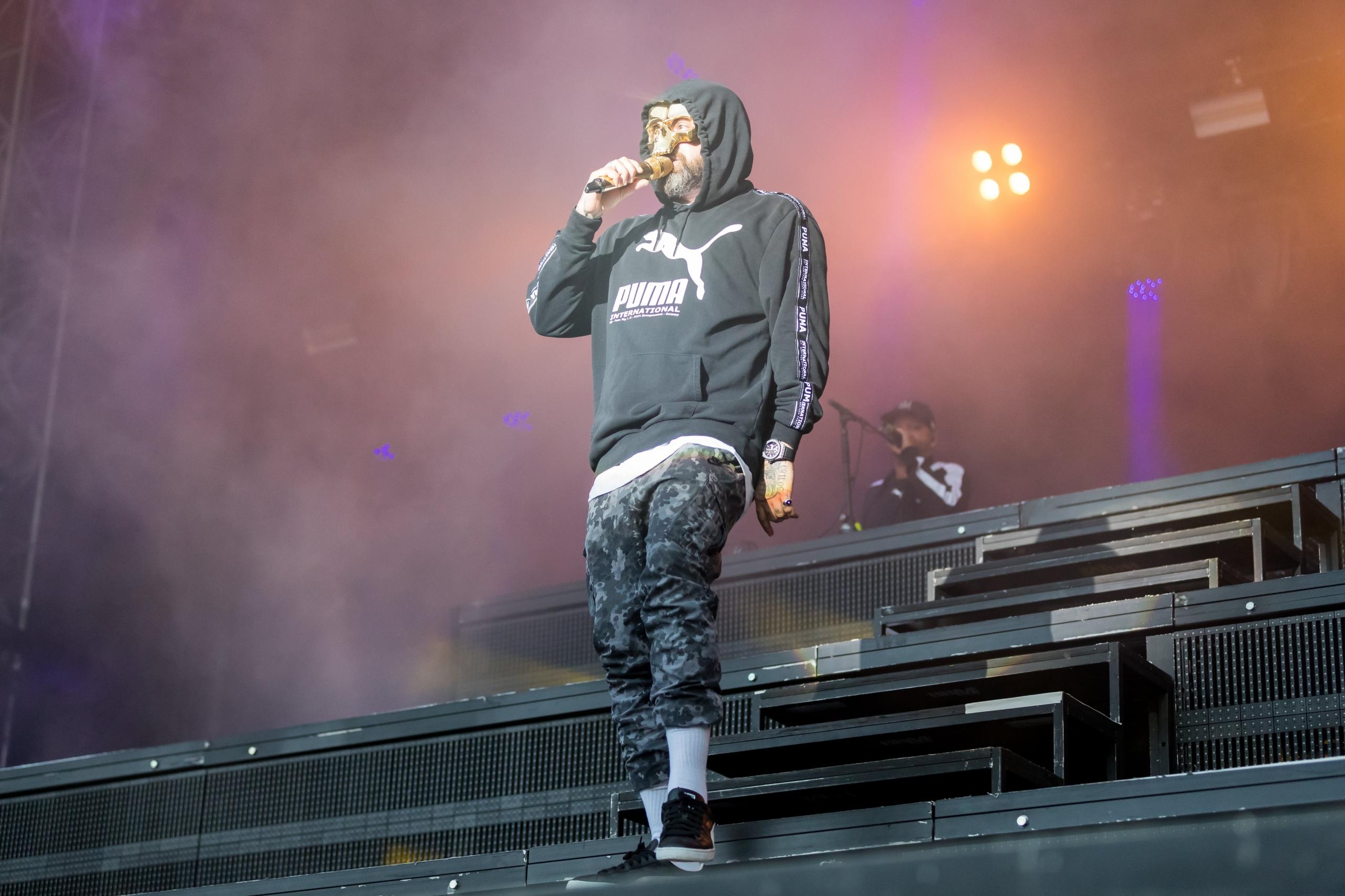 Der HipHopper Sido steht mit einem Mikrofon in der Hand auf einer Bühne und rappt.