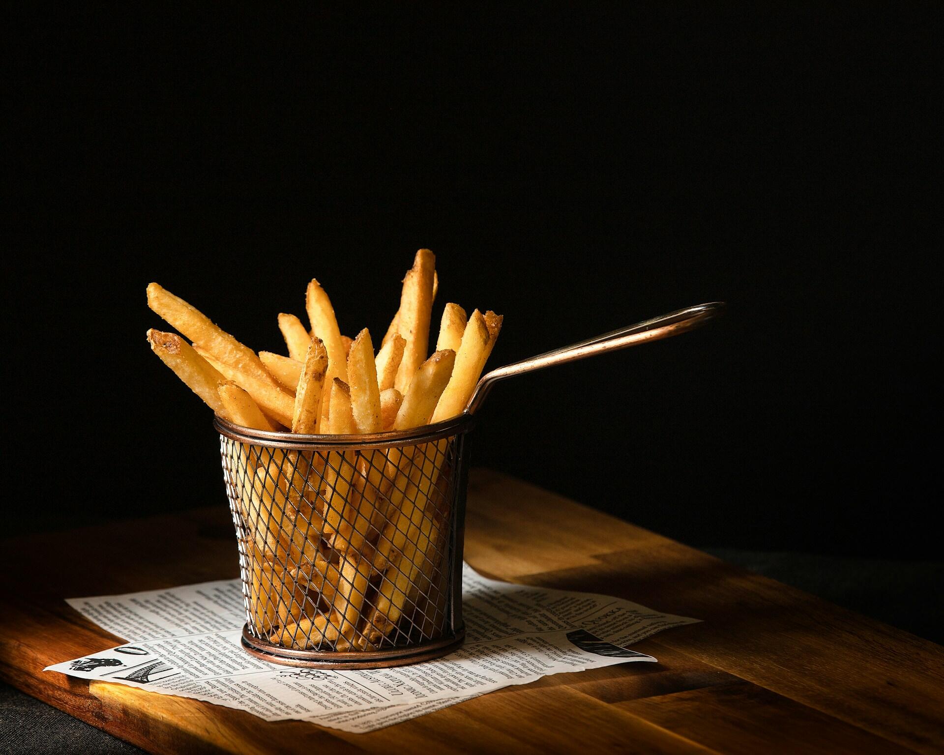 Korb mit Pommes auf Holztisch.