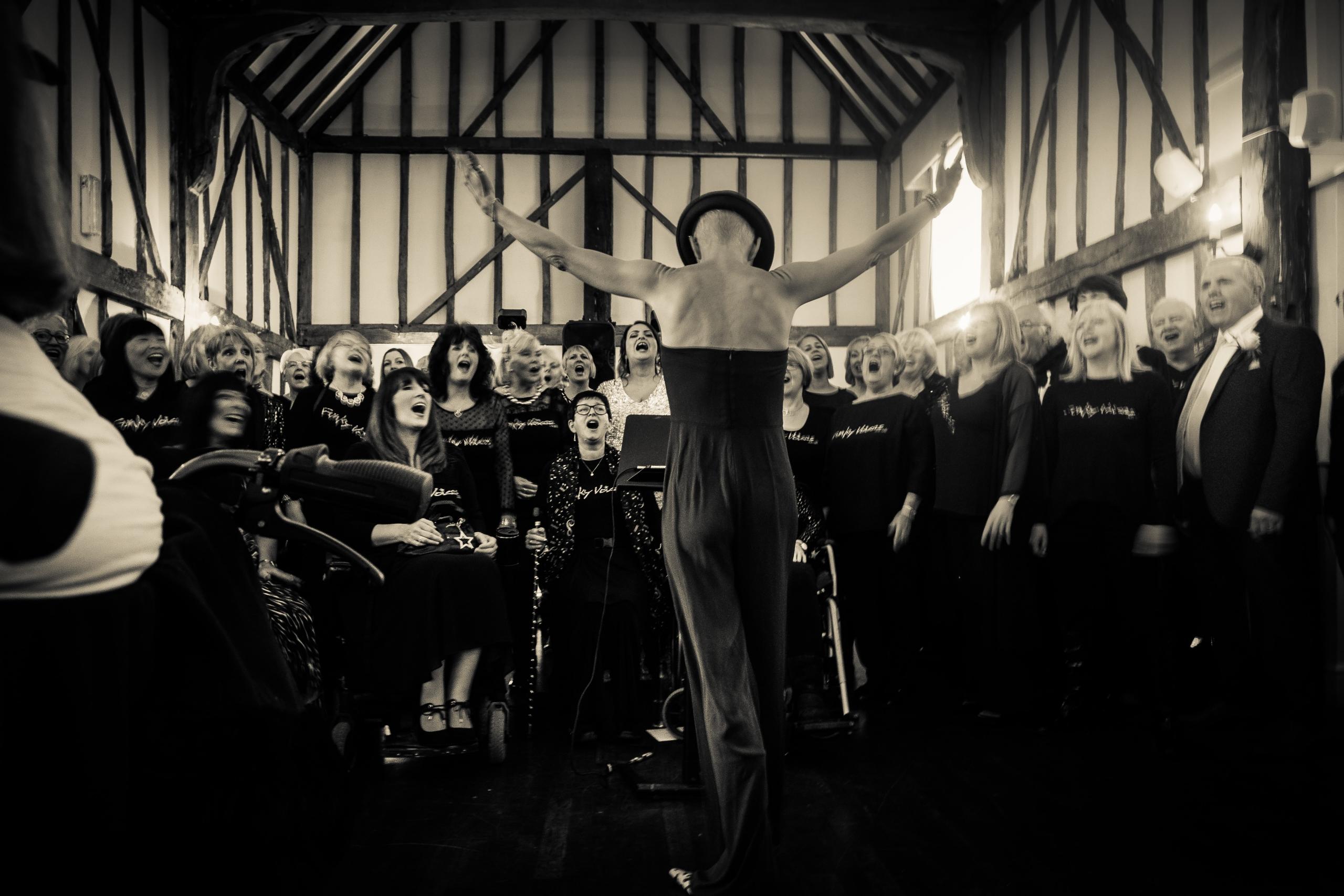 Sängerin in Abendkleid vor Chor. Musik verbindet und gemeinsam lassen sich der Gesang hoher und tiefer Noten gut üben.