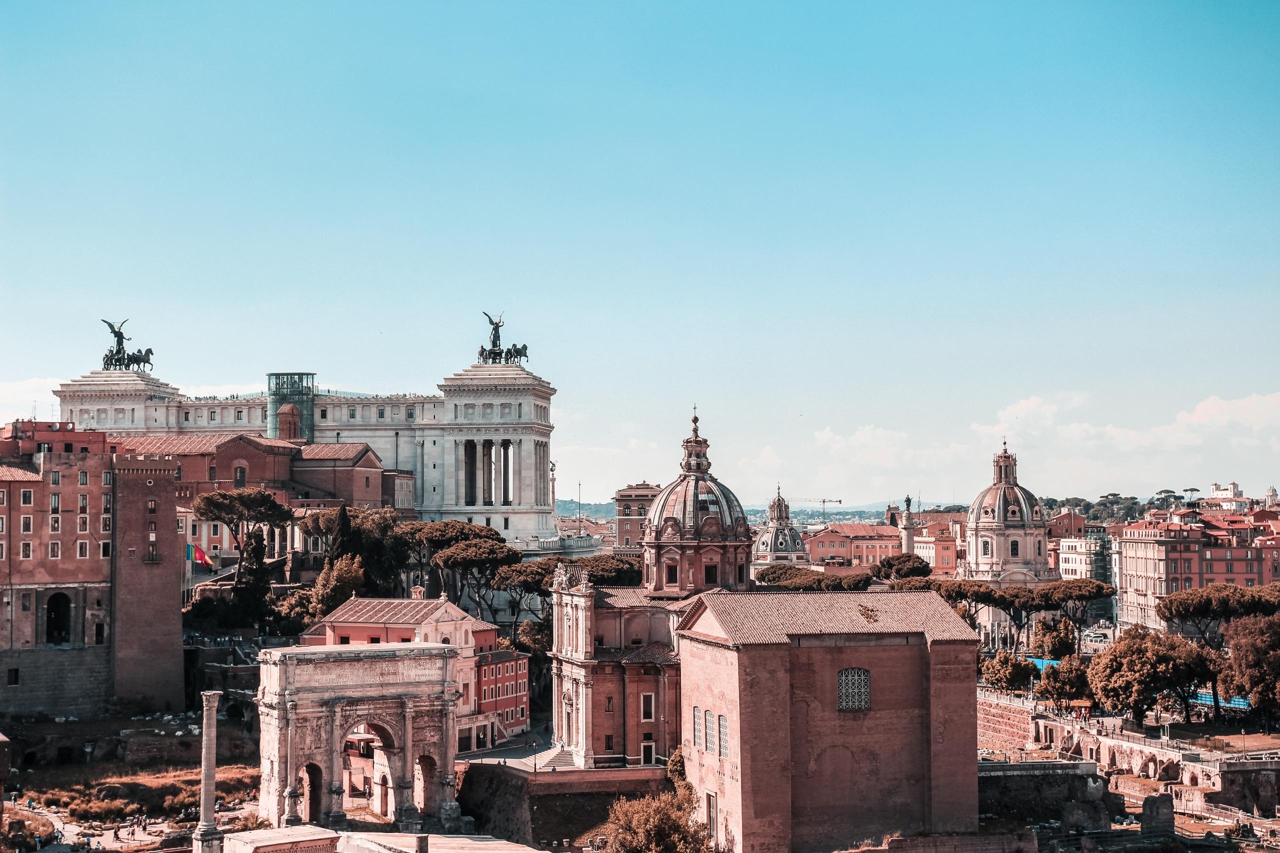 Antike Gebäude der Stadt Rom im Sonnenschein vor blauem Himmel. Die italienische Hauptstadt Rom ist einen Besuch wert.