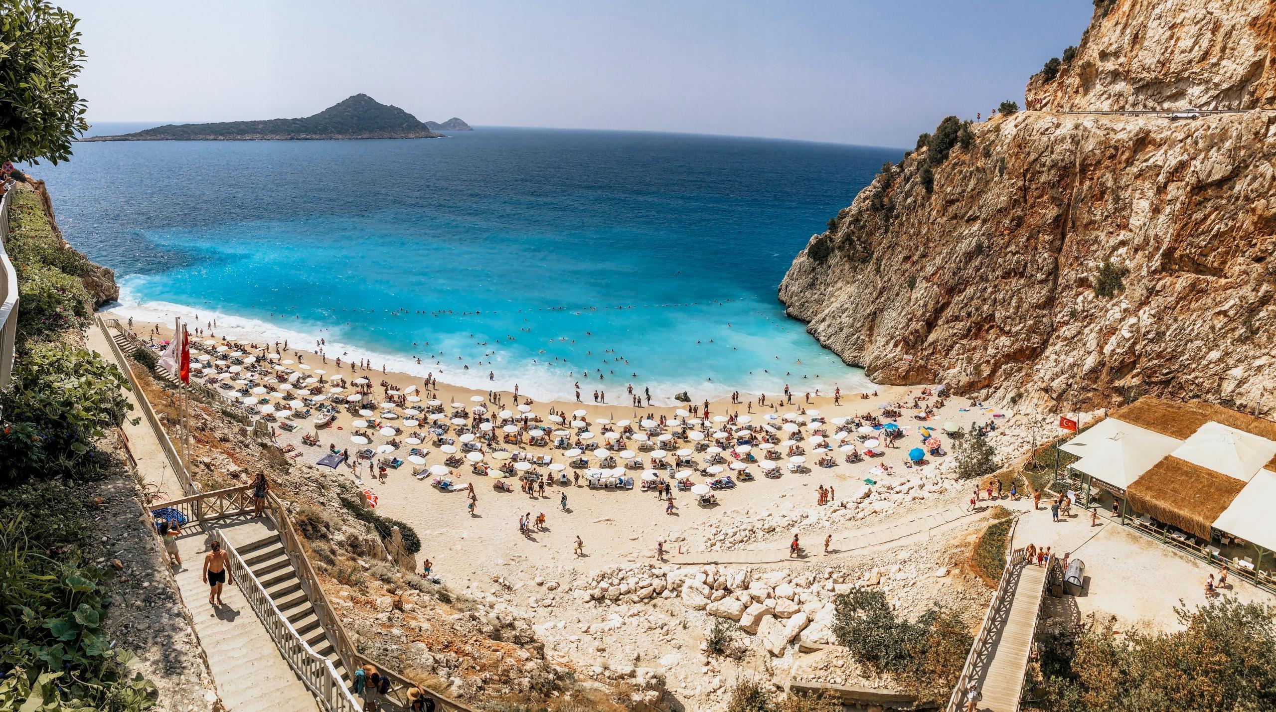 Ein Strand in Antalya mit einem tiefblauen Meer, der sehr beliebt ist bei Touristen.