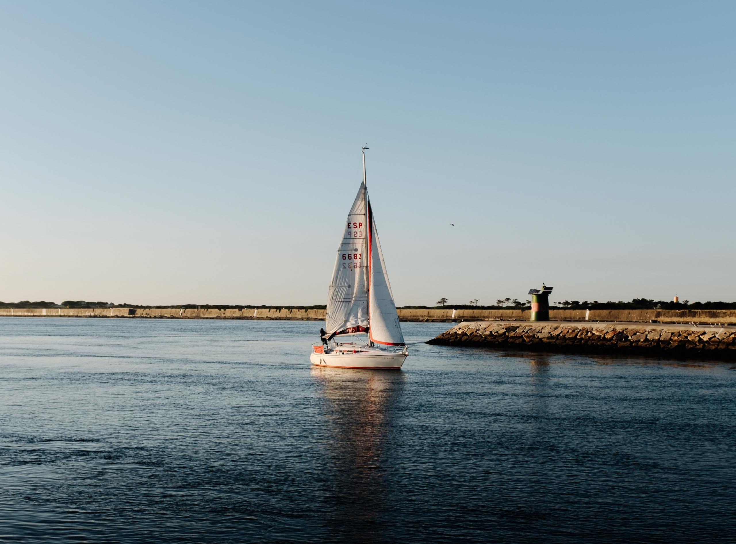 Ein Segelboot treibt vor der portugiesischen Küste umher. Wer Abenteuer mag, kann während der Reise nach Portugal auch auf dem Wasser schlafen!