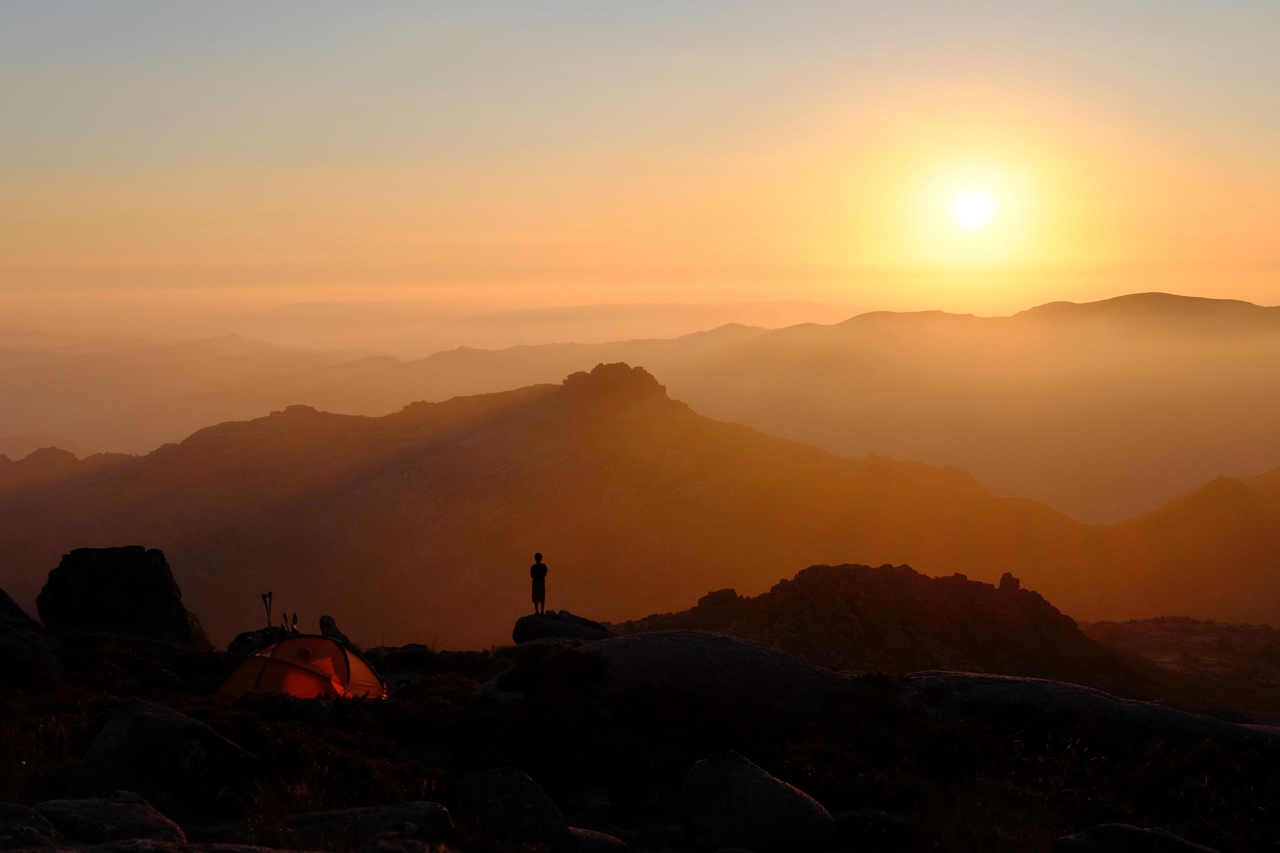 Ein Mann beobachtet, wie die Sonne über der portugiesischen Landschaft untergeht. Campen in Portugal kann eine tolle Erfahrung sein.