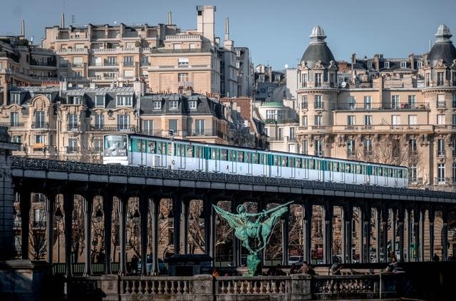 Pariser Metro fährt über Brücke, im Hintergrund typische Pariser Häuser. Informationen finden für das Arbeiten in Paris!
