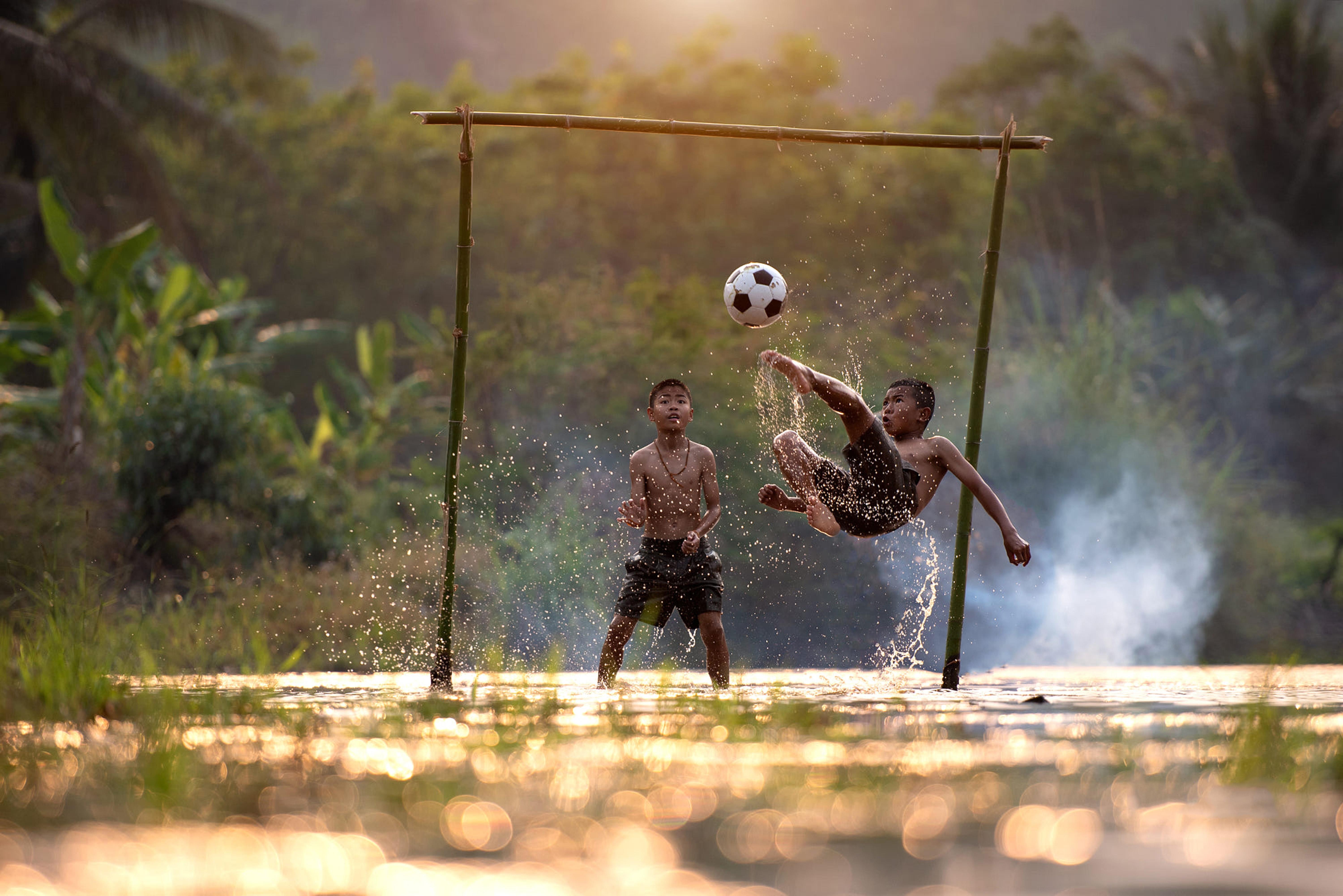 Zwei Kinder spielen auf ein Bambustor Fußball. Egal wo ihr seid, Fußball verbindet uns alle.