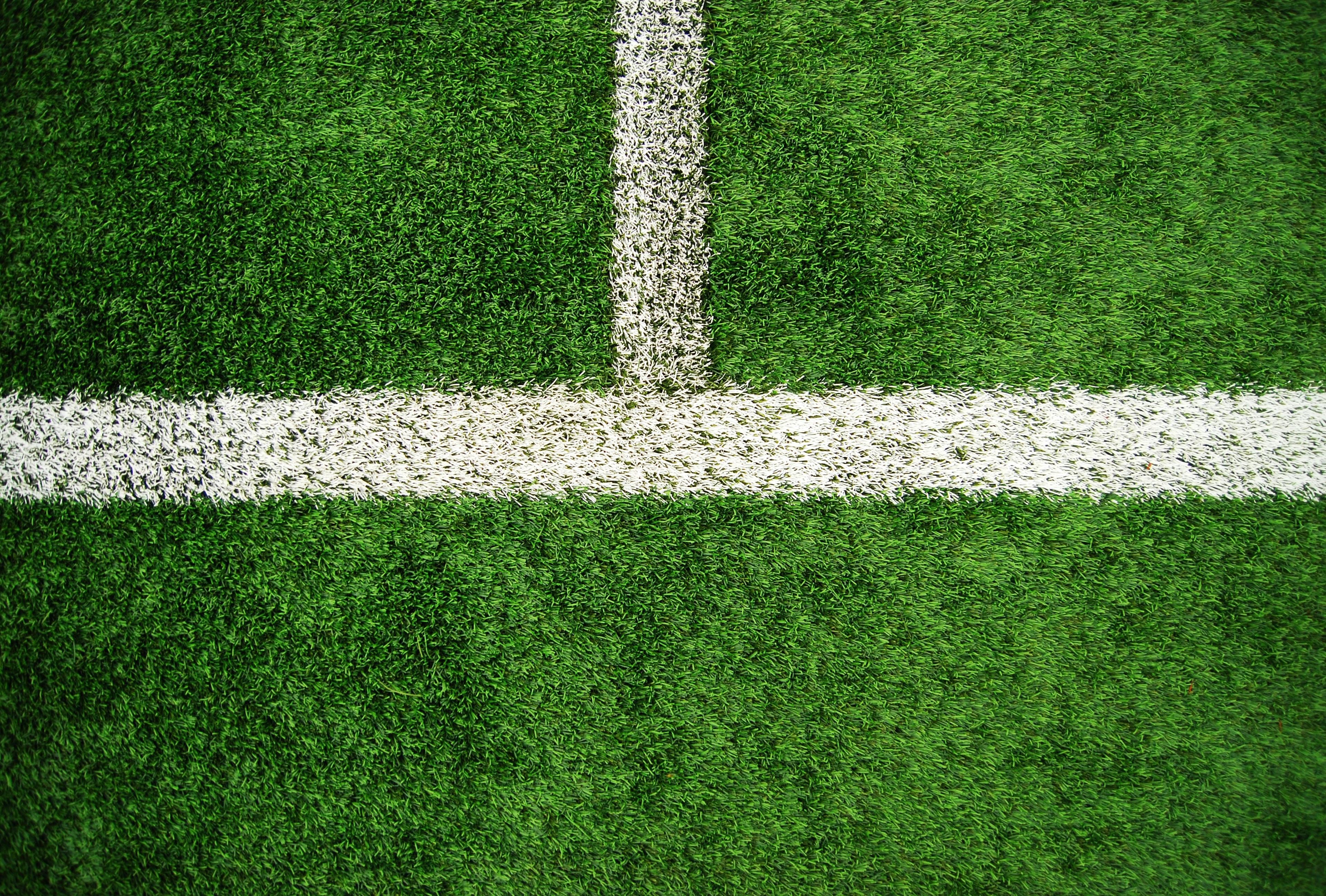 Die weißen Linien eines Fußballfeldes. Taktik im Fußball orientiert sich häufig an den Grund- und Mittellinien.