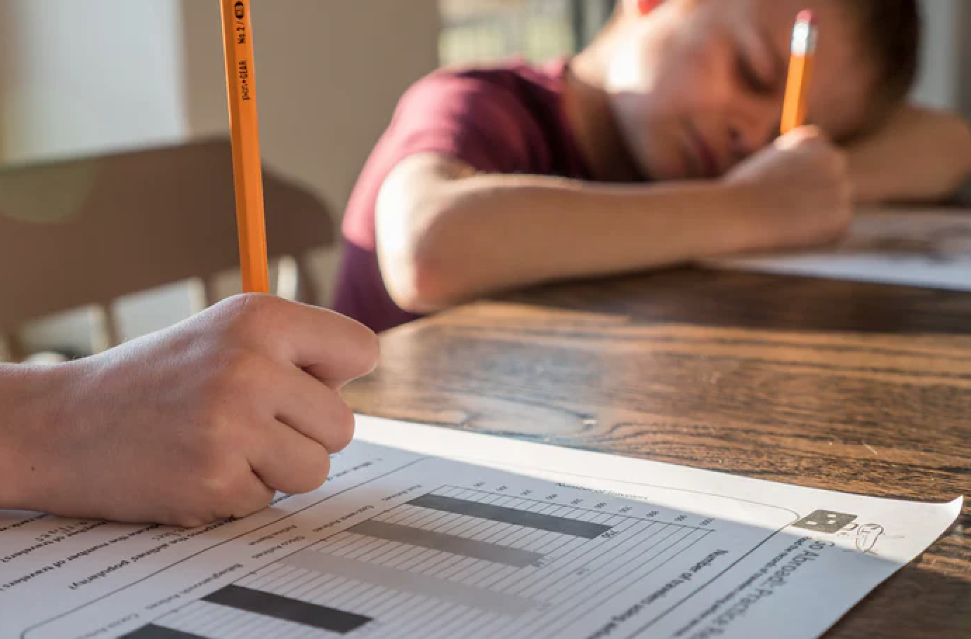 Kinderhände schreiben mit Bleistiften auf Arbeitsblättern mit Balkendiagrammen darauf. Wie kommt mein Kind gut durch die Grundschule?