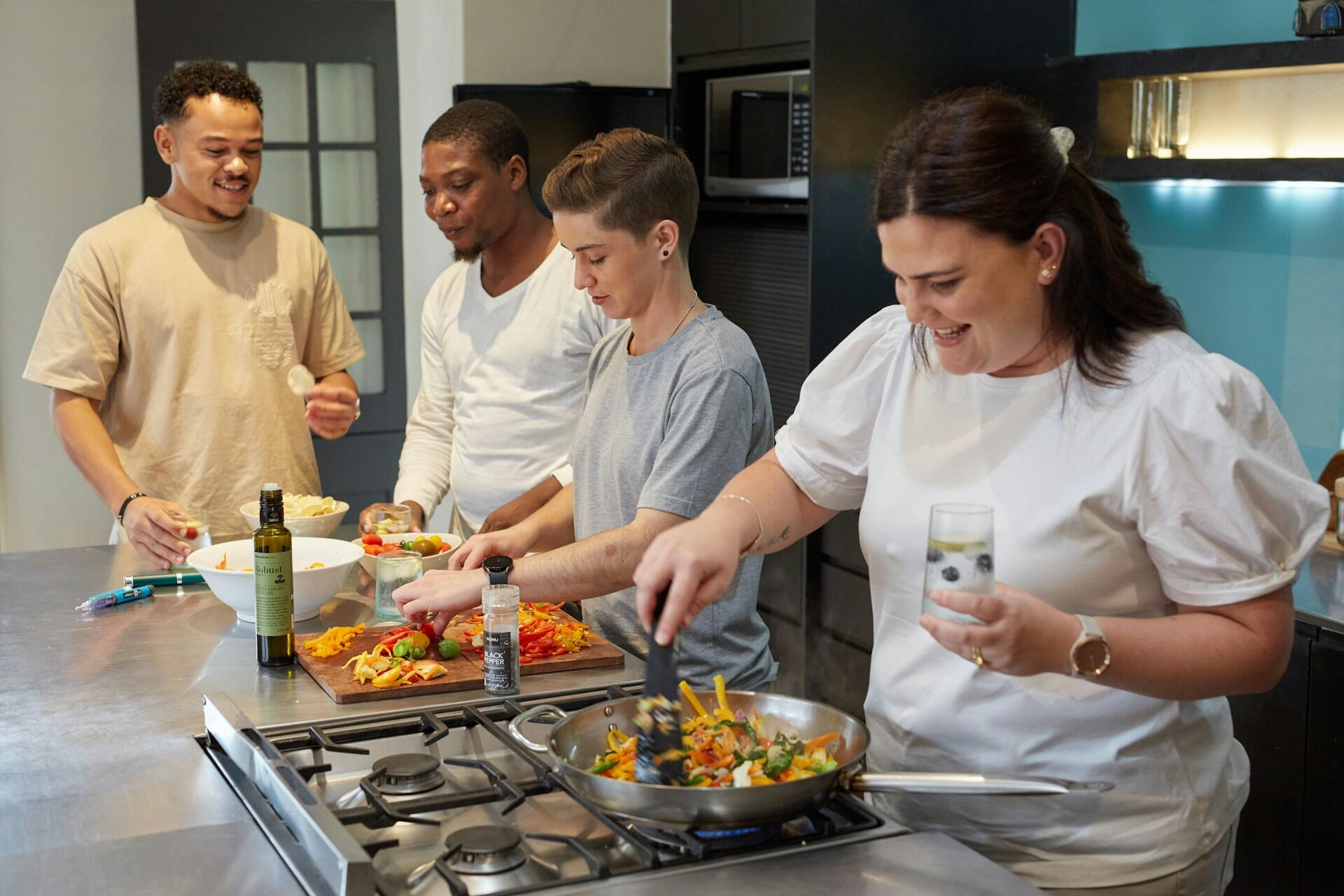 Gruppe von Menschen beim Kochen in einer Ferienwohnung