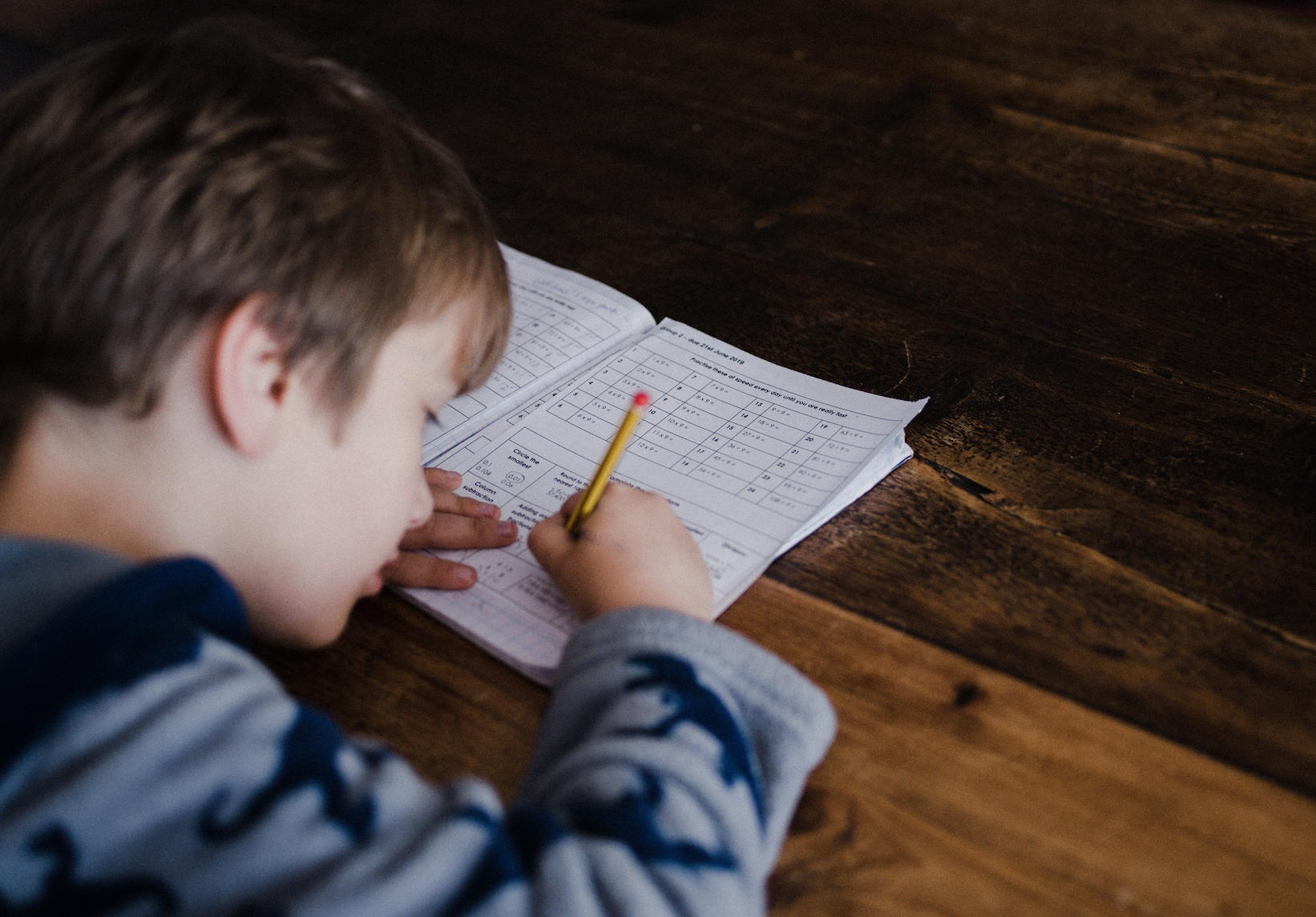 Ein Junge schreibt in sein Hausaufgabenheft.