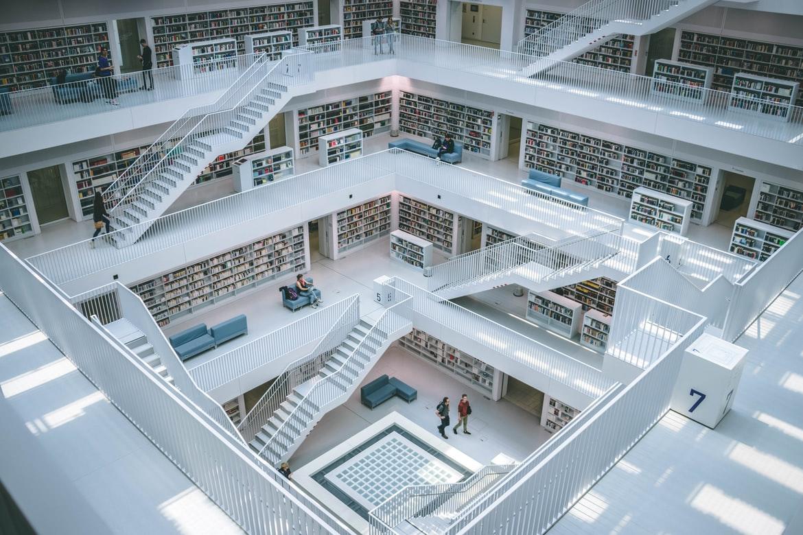 Das Bild zeigt die Bibliothek in Stuttgart, die von einer beeindruckenden Architektur geprägt ist: Treppen und Bücherregale bilden Quadrate über mehrere Stockwerke. Bibliotheken werden von Studierenden der Germanistik und der Literaturwissenschaft häufig besucht.