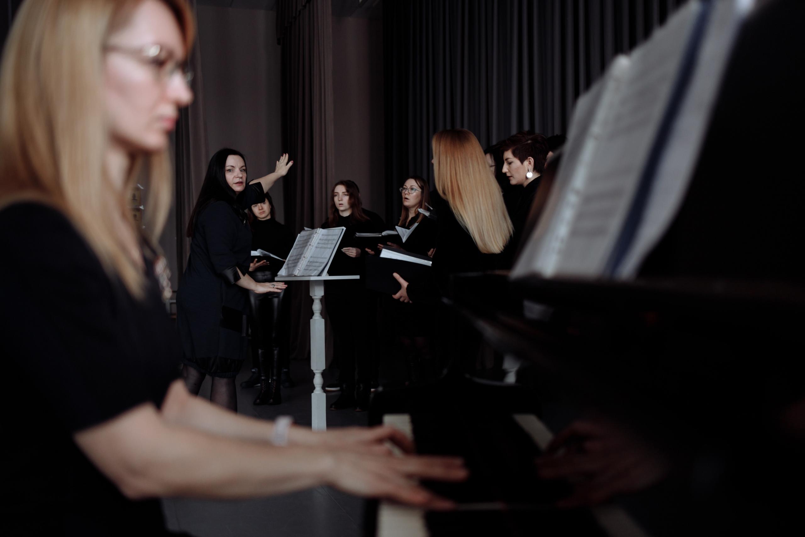 Diese Frau begleitet einen Chor auf dem Klavier. In der Korrepetition erstezt der Pianist das Orchester oder die Band, die bei dem Konzert den Chor begleiten wird.