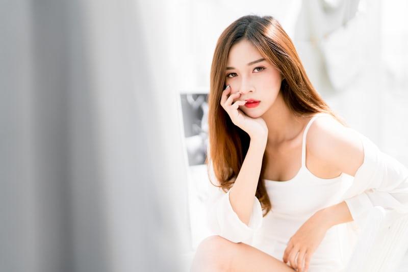 Eine junge koreanische Frau, perfekt gestylt und geschminkt, in einem weissen Kleid. K-Beauty ist in aller Munde.