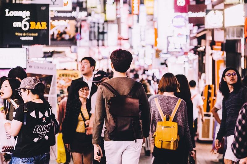 Strassenszene in Seoul. Menschen spazieren in einer Einkaufsstrasse unter Schildern mit koreanischen Schriftzeichen. Koreas Mentalität ist eine Mischung aus Tradition und Moderne.