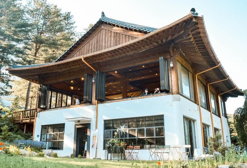 Ein grosses, traditionelles koreanisches Haus, in einem Garten mit alten Bäumen. Das Haus beherbergt ein Café.