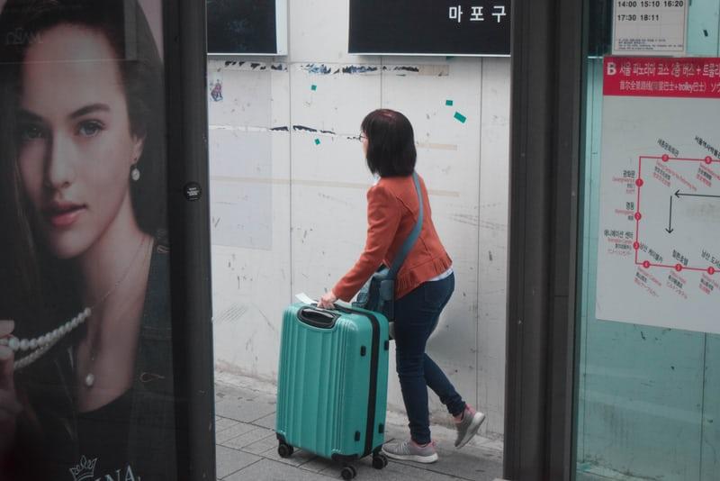 Eine Frau schiebt ihren Koffer durch eine koreanische Bahnstation.