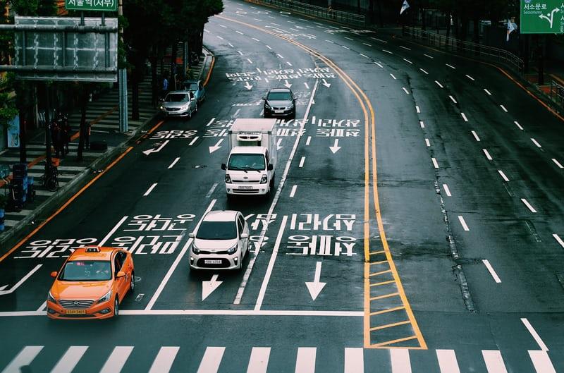 Eine koreanische Strasse aus der Vogelperspektive, mit Autos und koreanischen Schriftzeichen auf der Strasse.