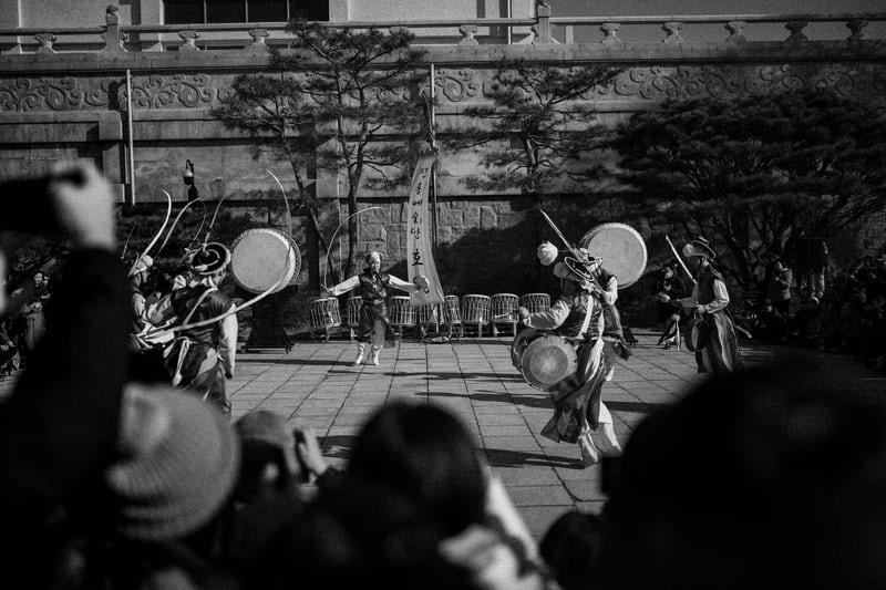 Koreanische Musiker spielen mit traditionellen Instrumenten auf einem Platz. 