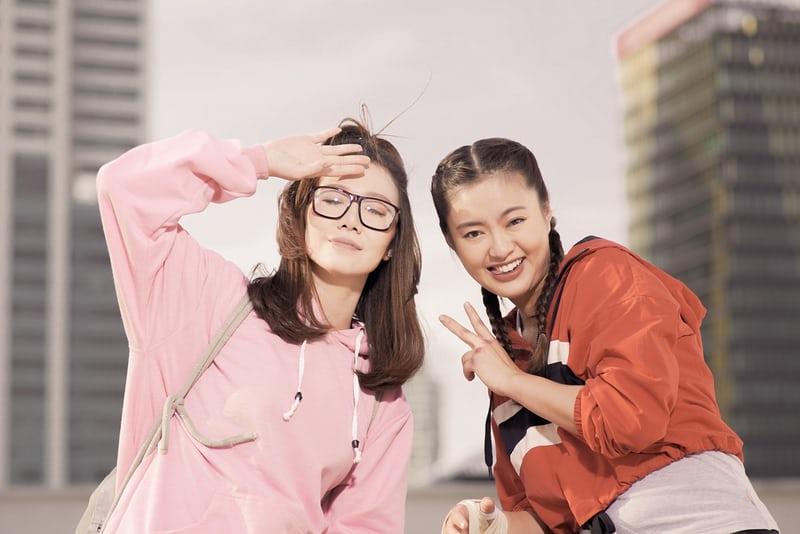 Zwei junge, koreanische Frauen machen Quatsch und lachen in die Kamera. 