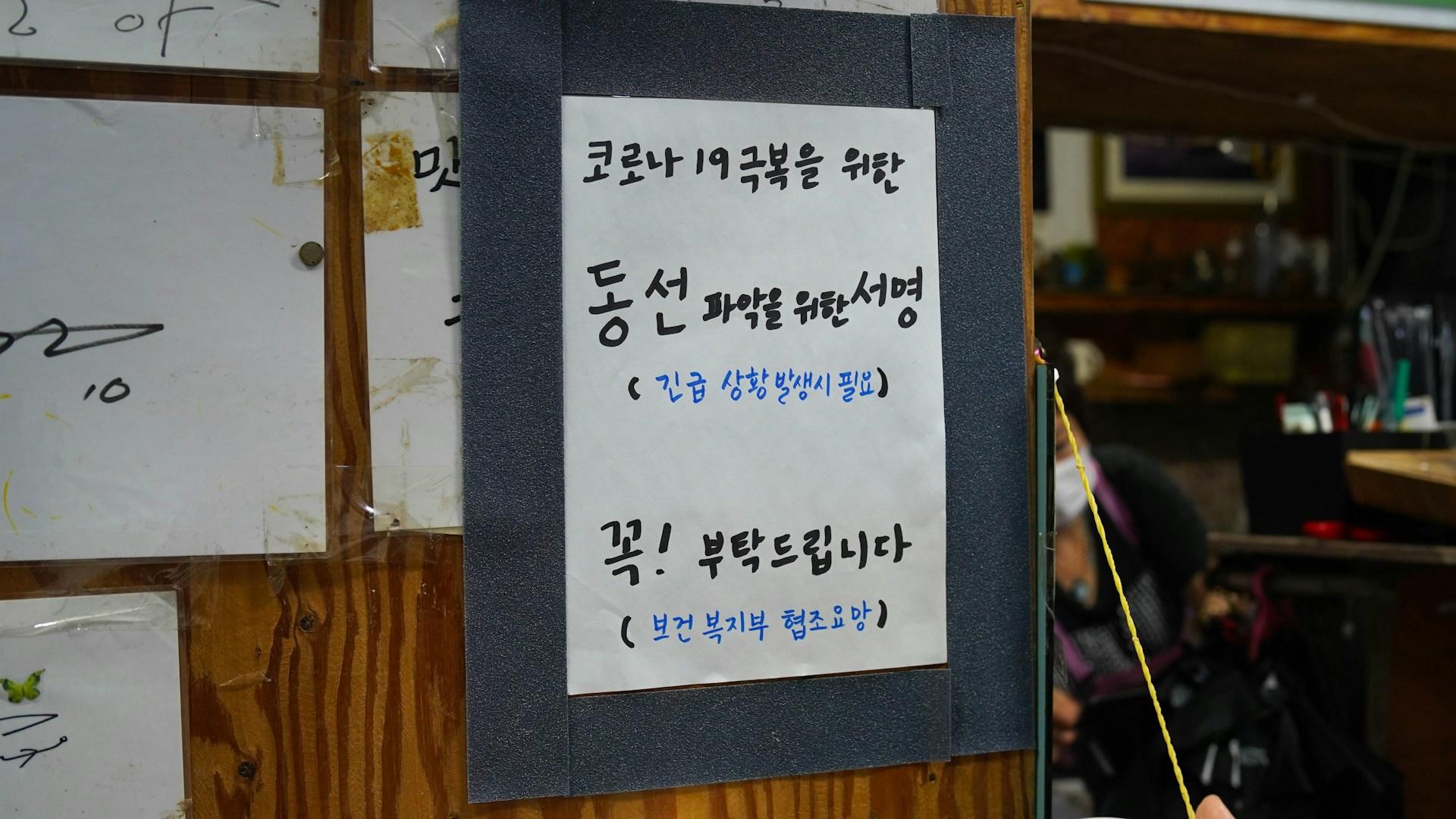 Ein weisses Schild mit koreanischen Schriftzeichen. Das koreanische Alphabet lernst Du schnell.