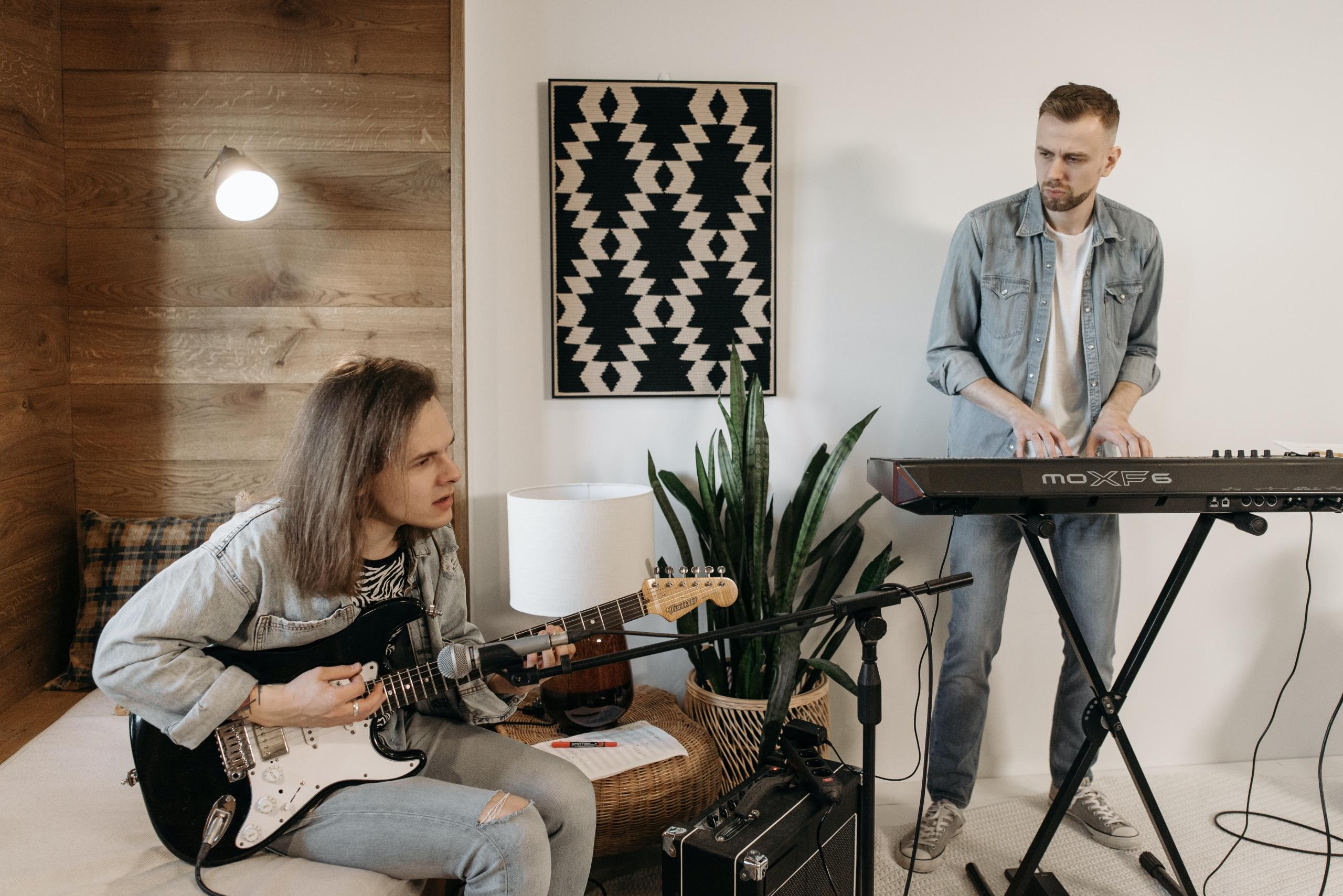 Hier proben ein Gitarrist und ein Pianist zusammen. Musikschulen fördern das gemeinsame Musizieren.