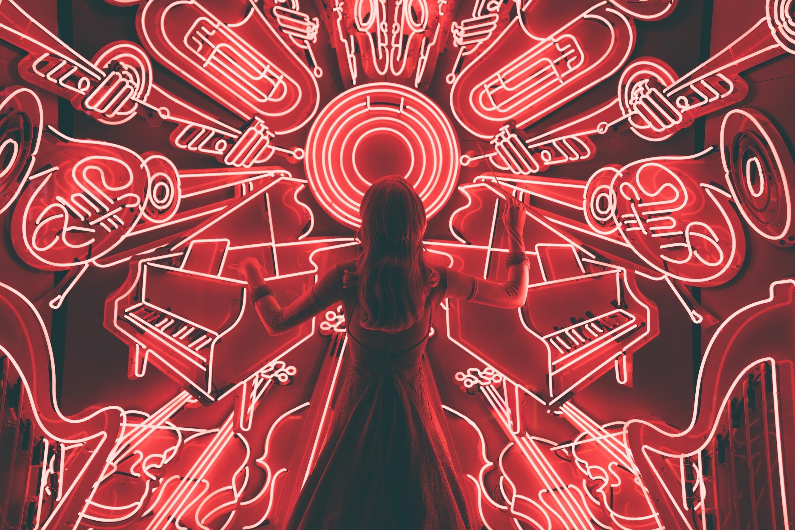 Eine Frau steht vor einer Wand mit leuchtenden Instrumenten. Ähnlich vielseitig sind Deine beruflichen Möglichkeiten nach einem Musikstudium.