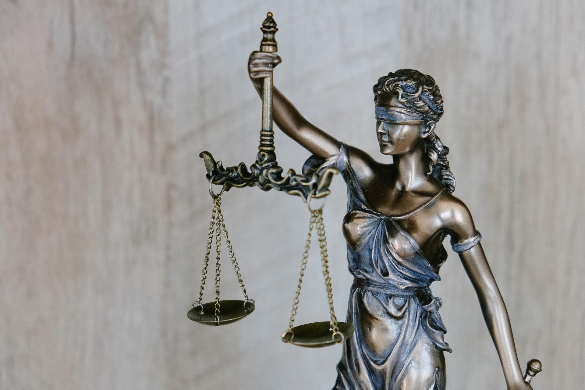 Eine Bronzestatue trägt eine Waage in der Hand und symbolisiert die ausgeglichene Bilanz eines Unternehmens