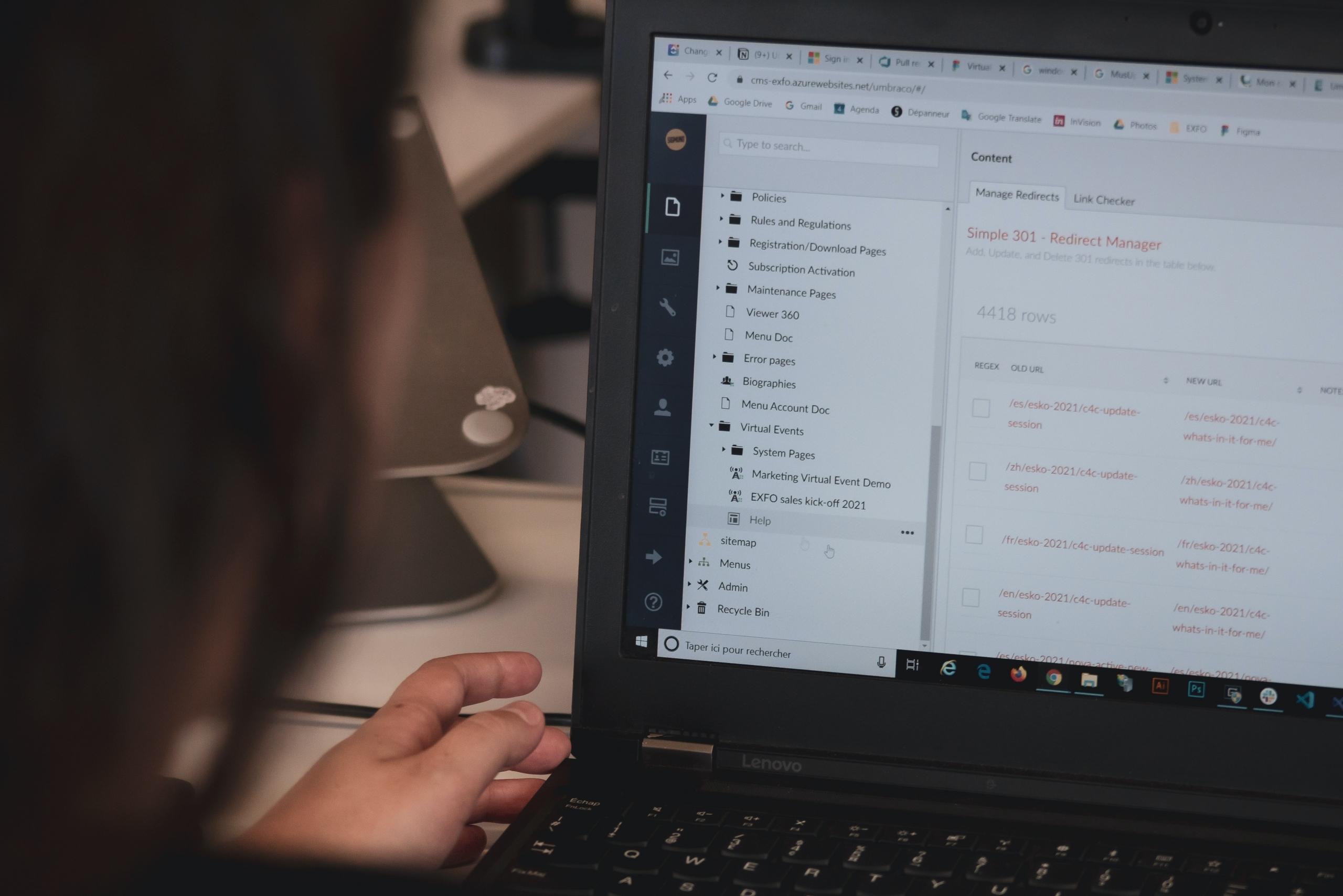 Foto von einer Person, die vor einem Computer mit einem Content Management System arbeitet.