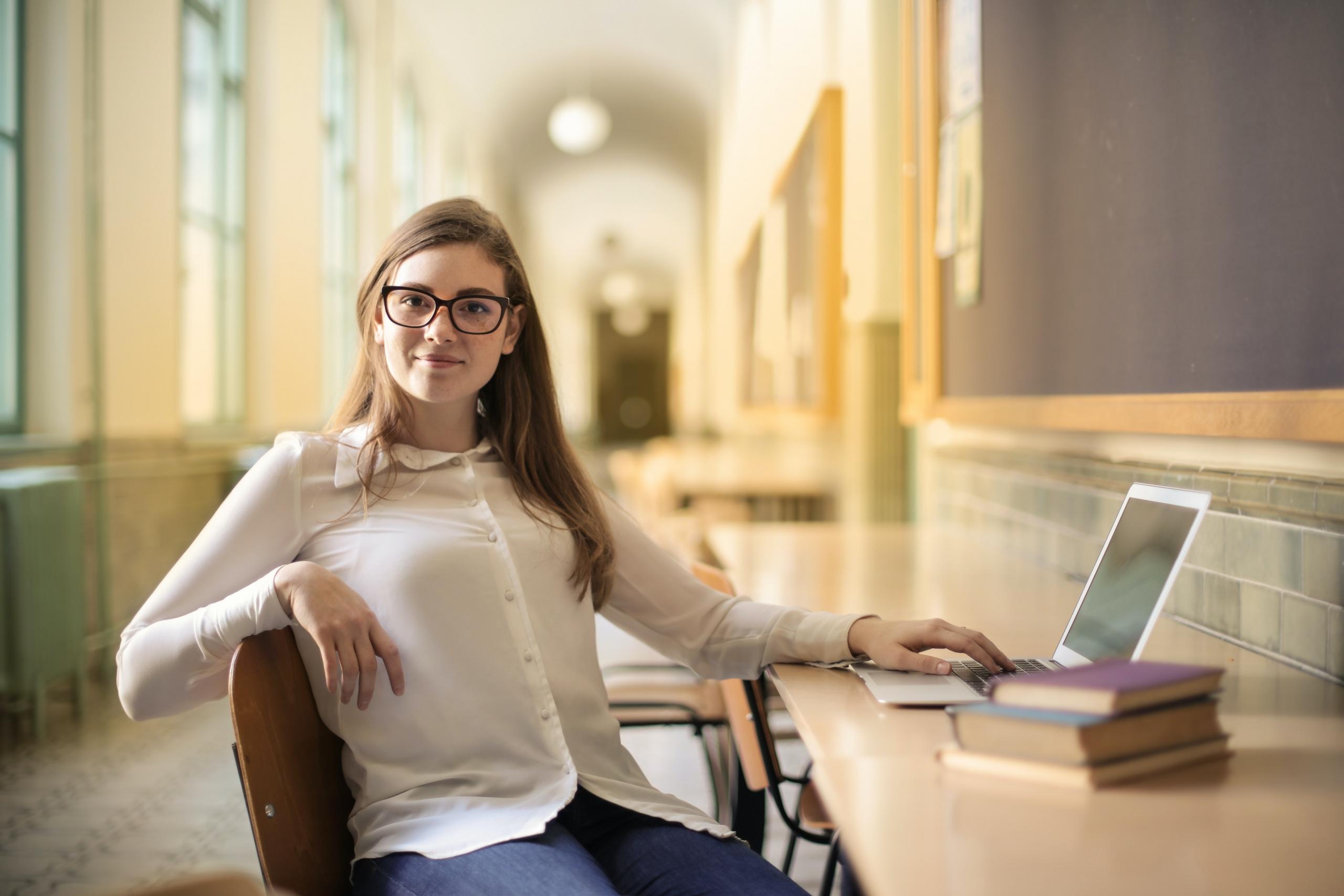 Eine Frau sitzt an einem Computer, neben den Bücher liegen.