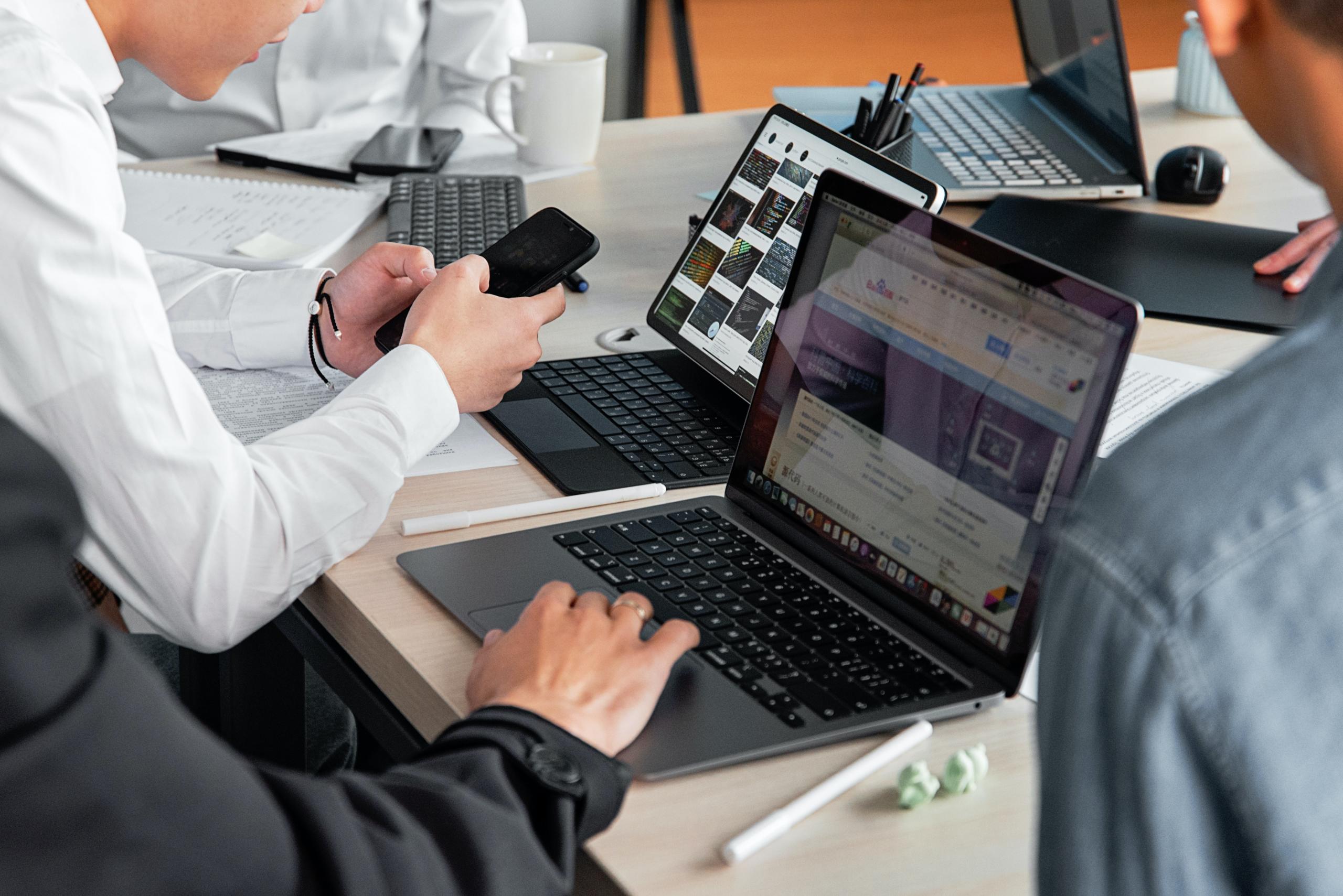Eine Gruppe von Personen arbeitet gemeinsam an verschiedenen IT-Geräten
