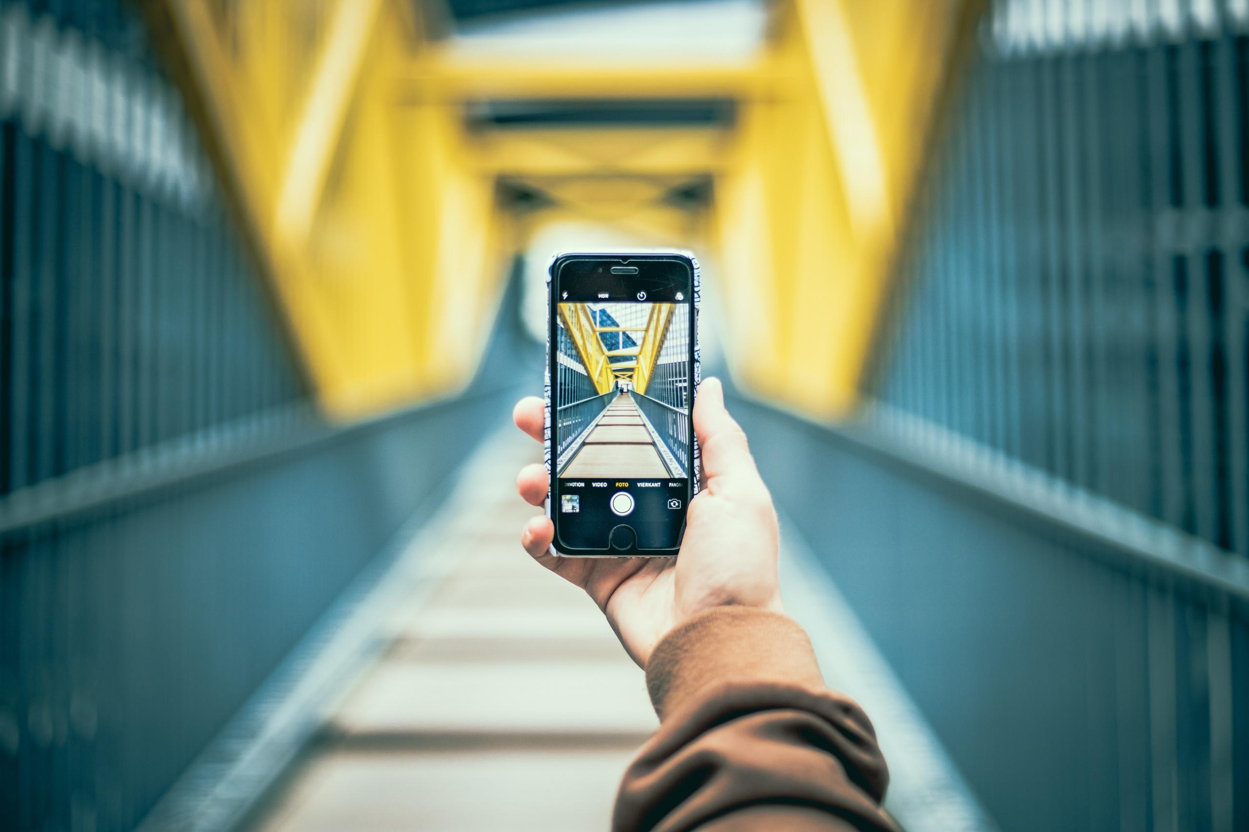 Durch die Kamera ist auf dem Display des Smartphones ist die gelbe Brücke im Hintergrund zu sehen.