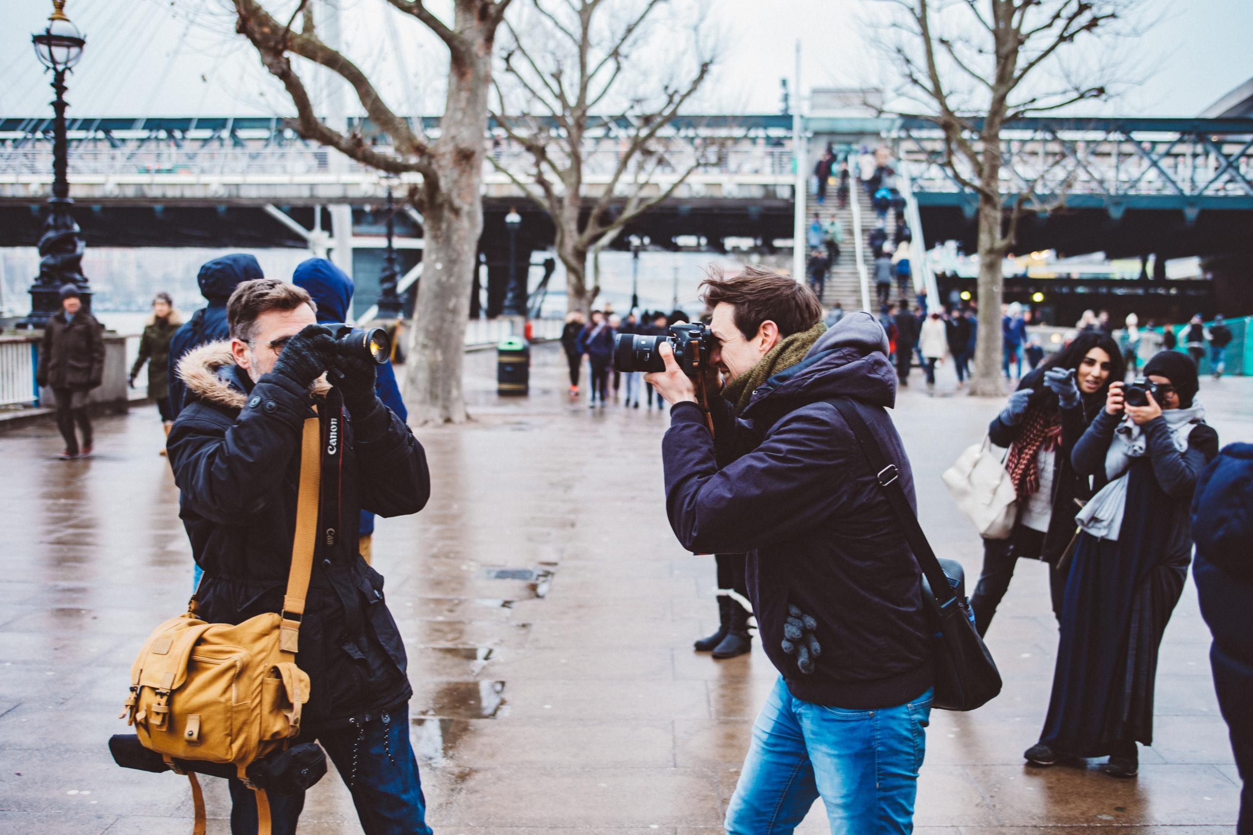 Auf einem öffentlichen Platz fotografieren sich zwei Männer gegenseitig.
