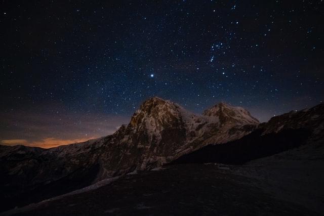 Sternenhimmel über markanten Bergspitzen und einem kleinen Streifen von letztem Abendrot über einem Bergrücken kann man im ältesten Nationalpark Italiens sehen.