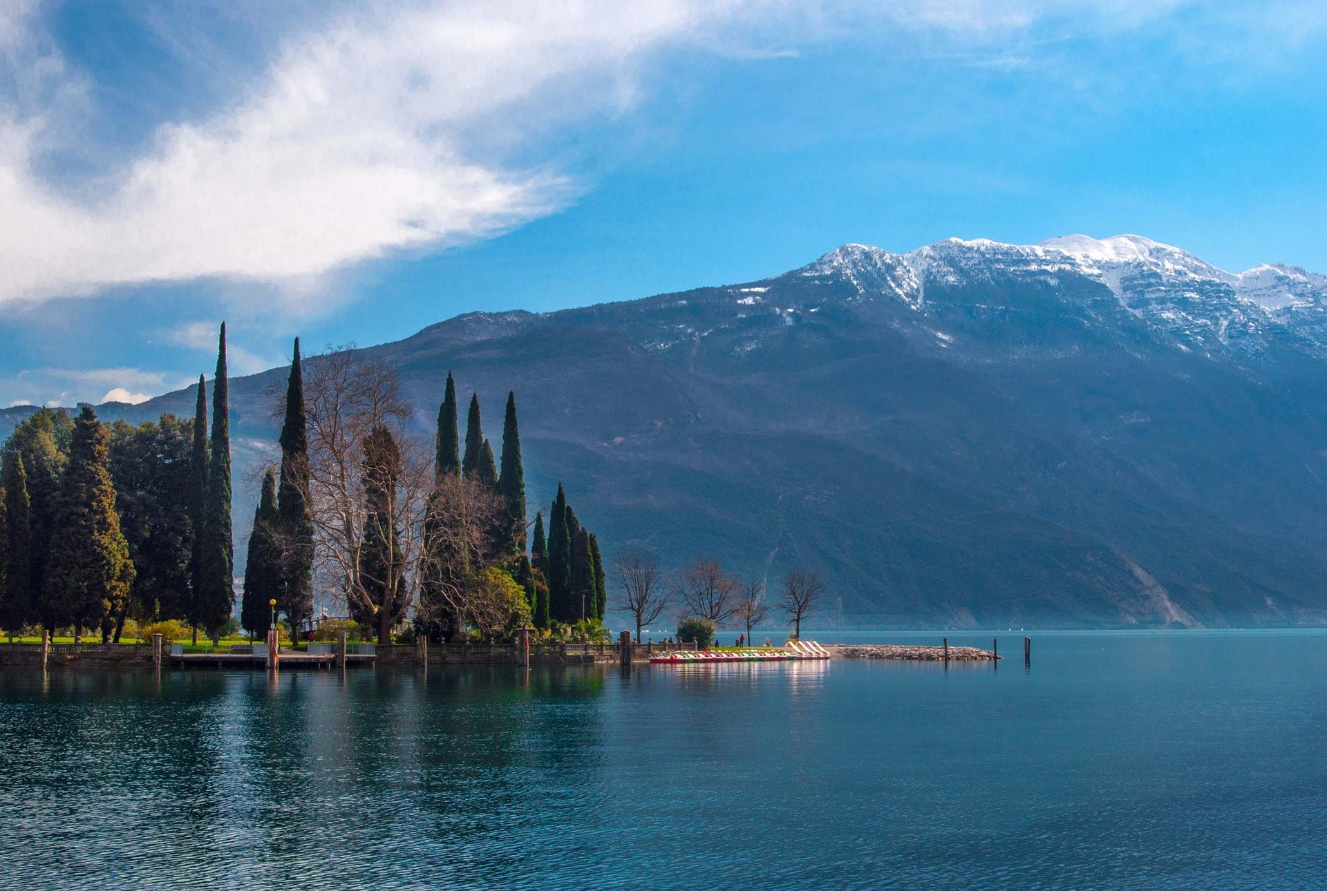 Ein tiefblauer Bergsee in der italienischen Lombardei mit den alpinen Bergen im Hintergrund