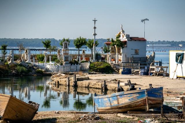 Blick über einen kleinen und alten süditalienischen Hafen mit einem Fischerboot im Vordergrund und einer Bucht im Hintergrund findet man in Apulien!