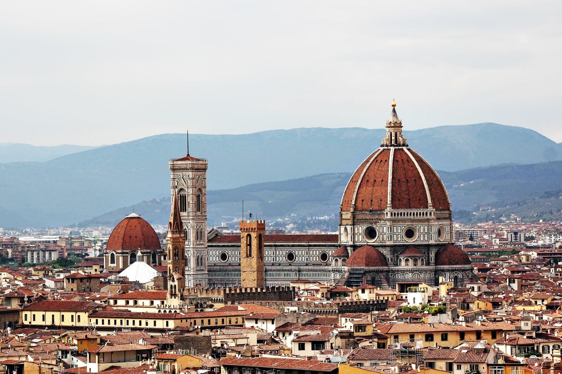 Der Dom von Florenz ragt über die Häuserspitzen der Altstadt hervor und lenkt vom Blick auf die Berge im Hintergrund ab