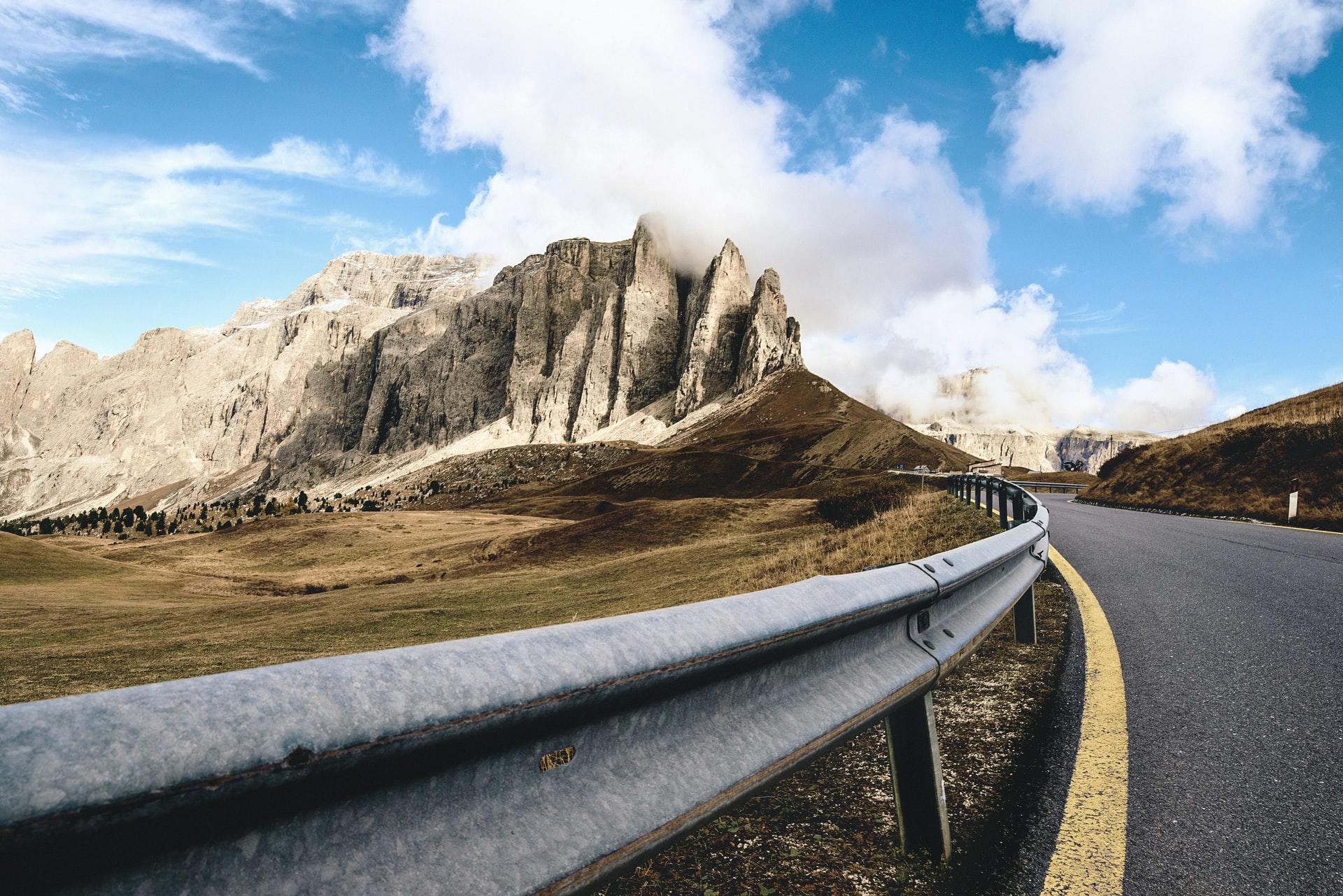 Einen Blick über eine Bergstraße auf eine imposante Bergformation kriegt man in den Dolomiten an vielen Orten!