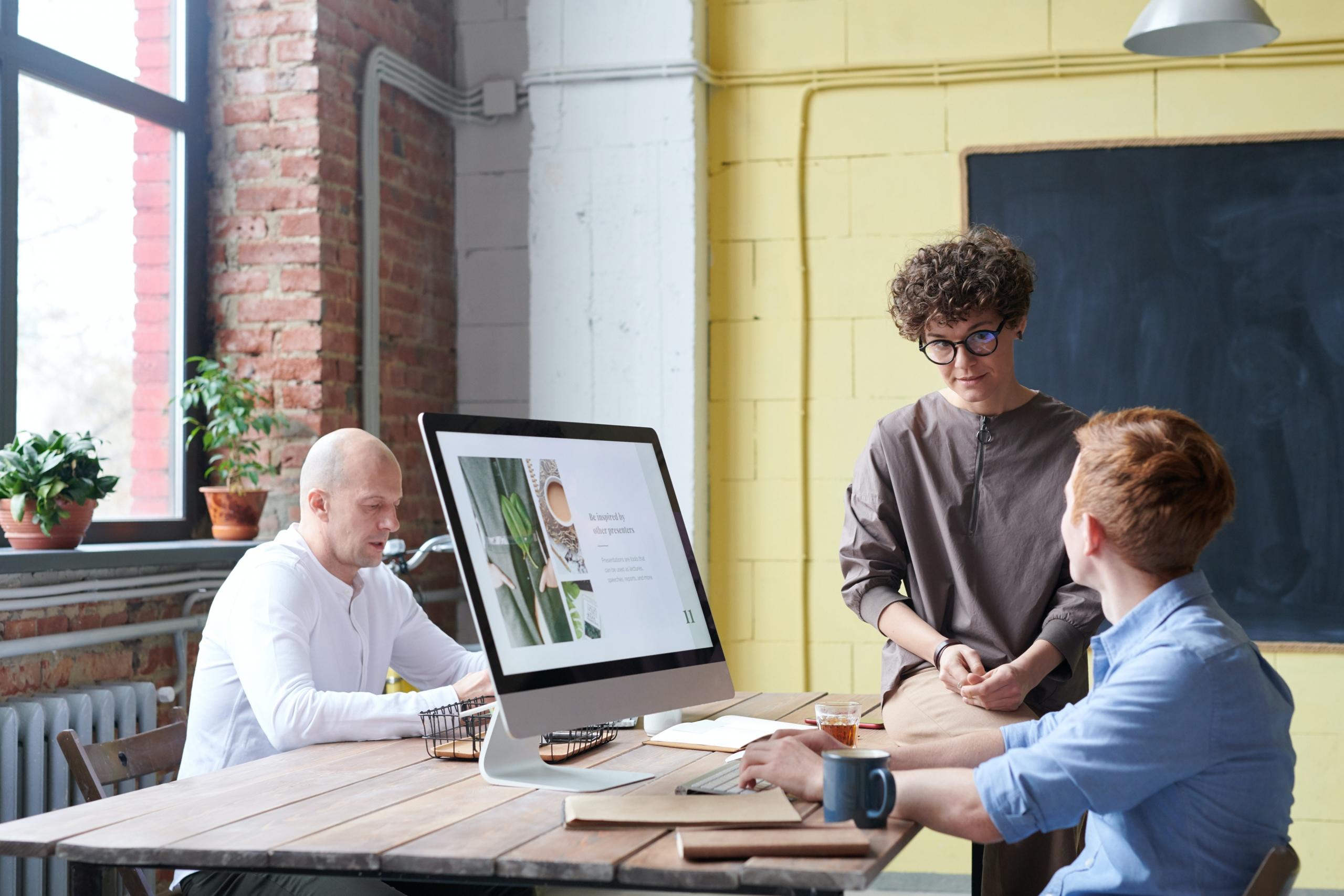 Drei Personen arbeiten gemeinsam in einem Raum an Computern