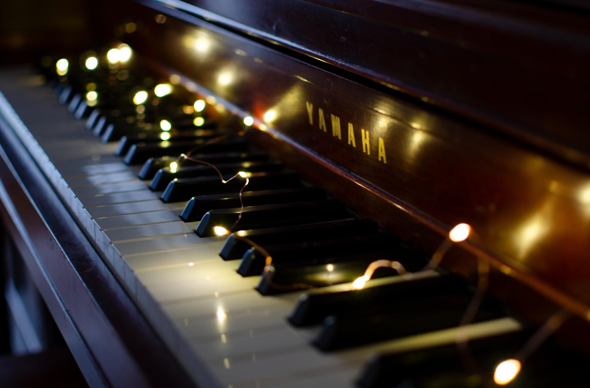 Ein Klavier der Marke Yamaha wird elegant von einer auf der Tastatur liegenden Lichtekette beleuchtet.
