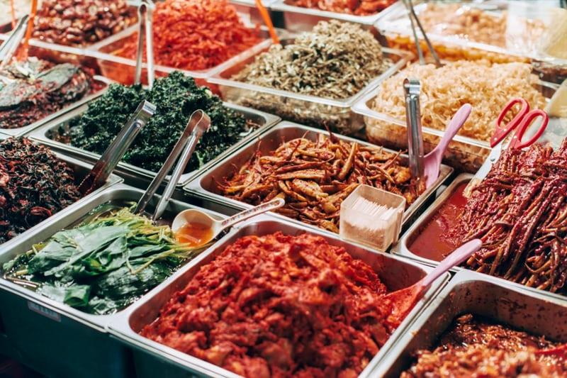 In grossen rechteckigen Metallschüsseln wie in einer Kantine, befinden sich verschiedene koreanische Banchansdene 