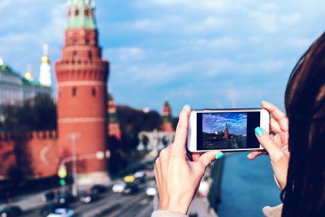 Möchtest du gerne die russische Sprache lernen? Reise doch wie diese junge Frau die mit ihrem Telefon eine Foto vom Kreml macht nach Moskau!