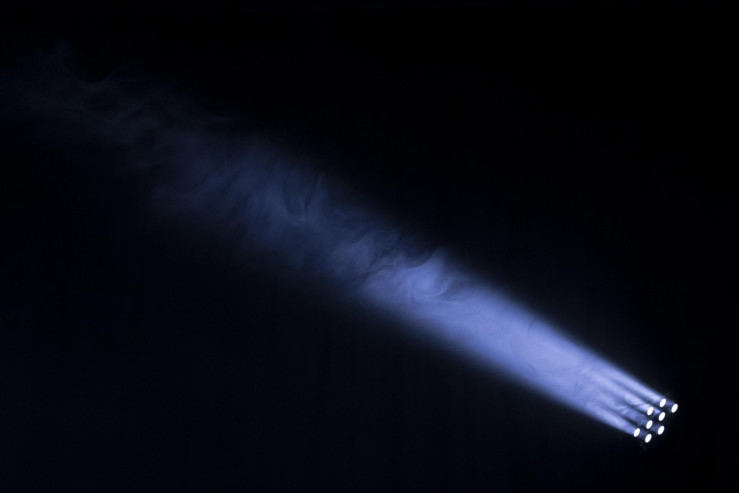 Der Lichtstrahl eines Scheinwerfers scheint hell in die Dunkelheit hinein.