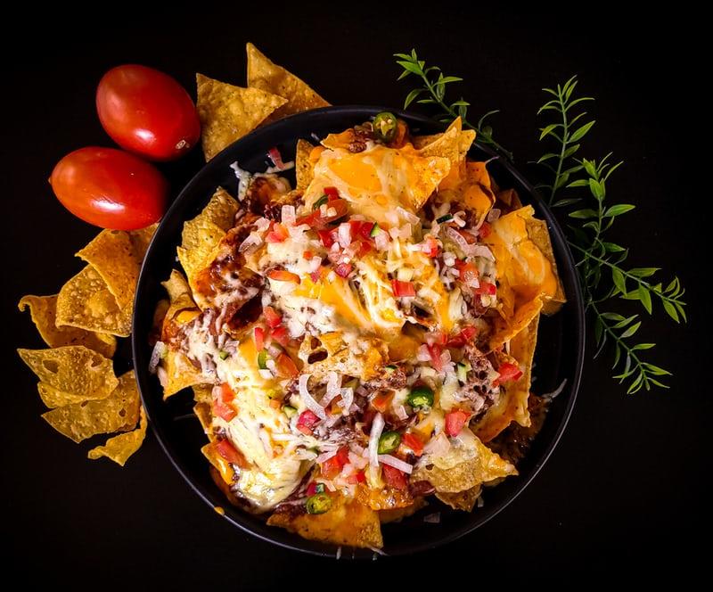 Auf einem Teller liegen Tortilla-Chips mit Topping.