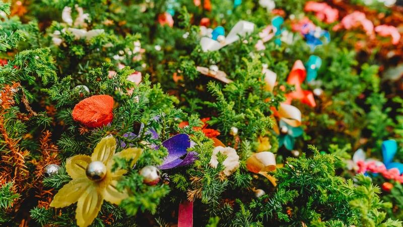 Eine immergrüne Pflanze geschmückt mit bunten und goldenen Papierblumen.