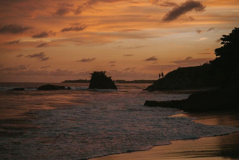 Sonnenuntergang über Meer mit Felsen.