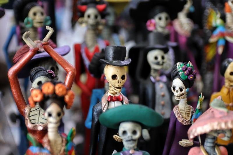 Viele geschnitzte bekleidete Skelettfiguren.