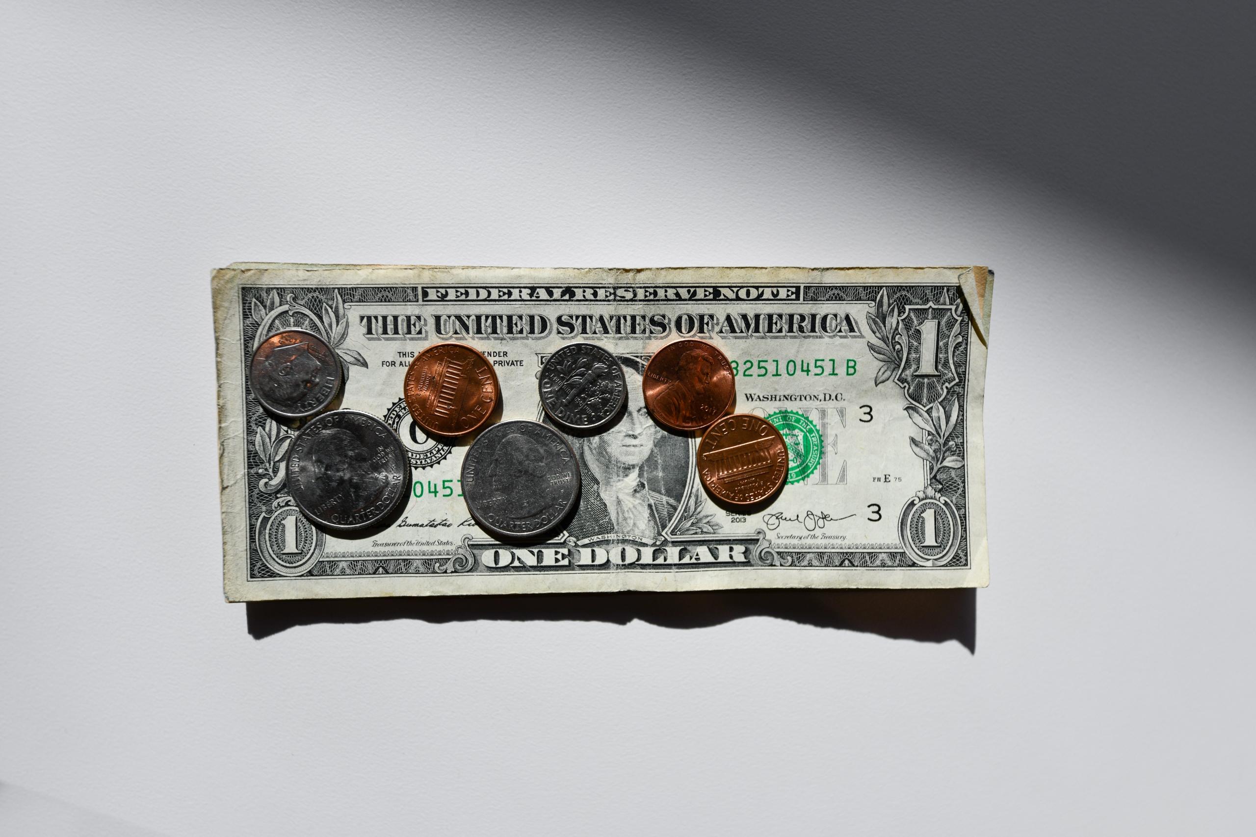 Sieben Münzen in Bronze und Silber liegen auf einem Ein-Dollar-Schein.