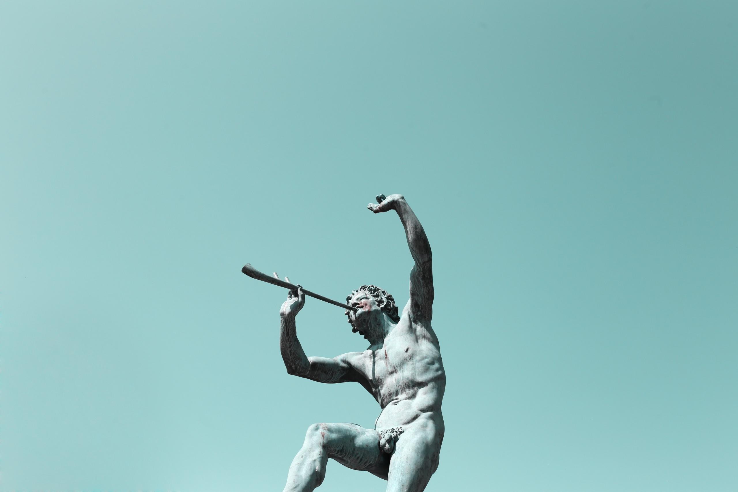 Eine nackte steinerne Statue, die Flöte spielt.